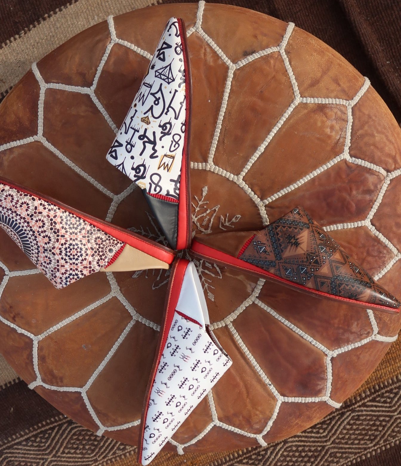 4 babouches air babouche marrakech de la collection bab atlas pour homme et femme, sur une pouf amazigh berbère